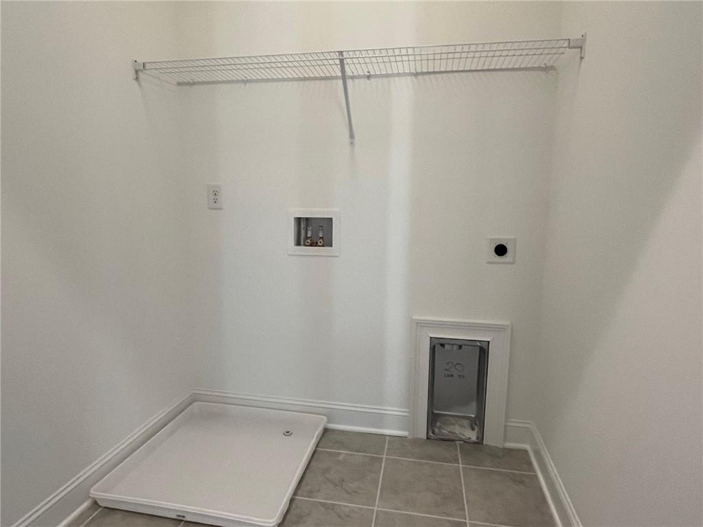 Clothes washing area featuring washer hookup, light tile floors, and hookup for an electric dryer