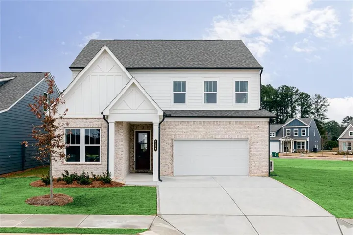 View of front of home featuring roof with shingles, brick siding, concrete driveway, a front lawn, and an attached garage