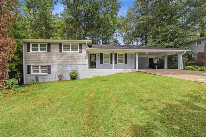 Split-level residence featuring a covered carport, a paved driveway, and mature landscaping