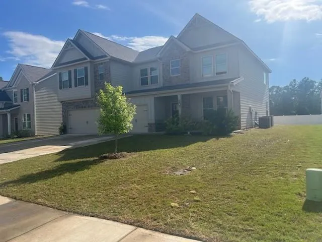 Two-story residence featuring a covered front porch, a two-car garage, and a combination of siding and stone exterior finishes