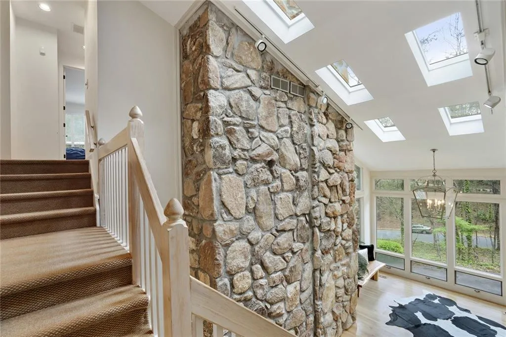 Staircase with high vaulted ceiling, a notable chandelier, skylights