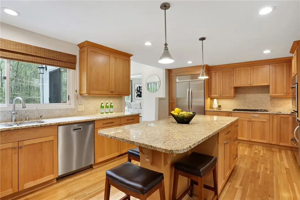 Kitchen with sink, a kitchen breakfast bar, backsplash, stainless steel appliances, and a center island