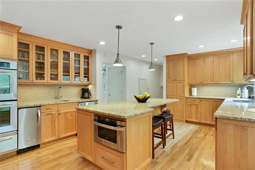 Kitchen with tasteful backsplash, light hardwood / wood-style floors, light stone countertops, and a center island