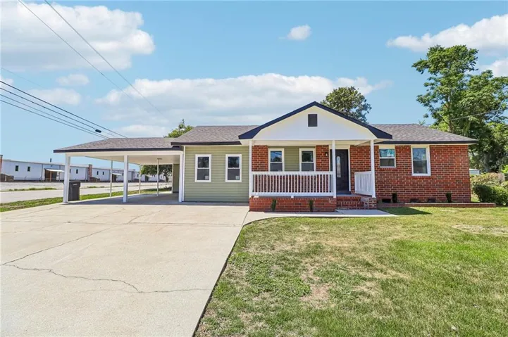 Brick and siding exterior, expansive concrete driveway, covered carport, covered front porch, and white railing