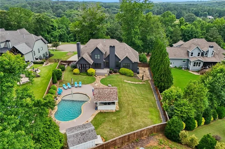 Elegant brick Colonial estate showcasing manicured grounds, mature landscaping with specimen trees, resort-style freeform pool with integrated spa, and expansive lawn with defined hardscaped patio areas