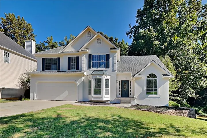 Stucco exterior with a two-car garage, bay window, and arched entry window