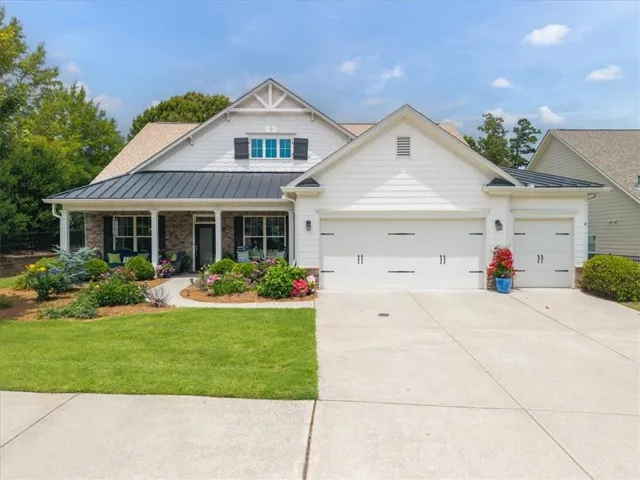 White siding exterior with a dark metal accent roof and a covered front porch with columns