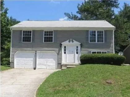 Two-story residence featuring gray siding, a white front entry, two garage doors, and an established front lawn