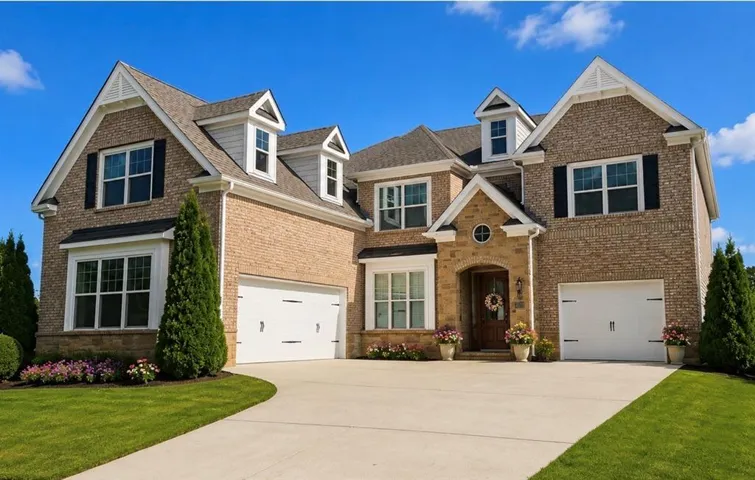Brick exterior with stone accents, multiple dormer windows, twin two-car garages, and a paved driveway