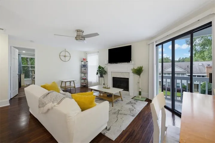 Hardwood-finish flooring, built-in fireplace with mantel, ceiling fan, and sliding glass door to exterior