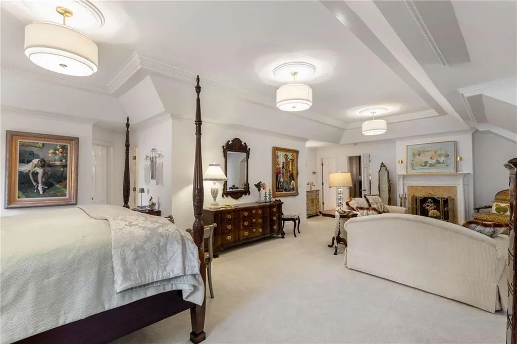 Oversized primary suite looking towards the sitting area, fireplace, and vaulted ceiling