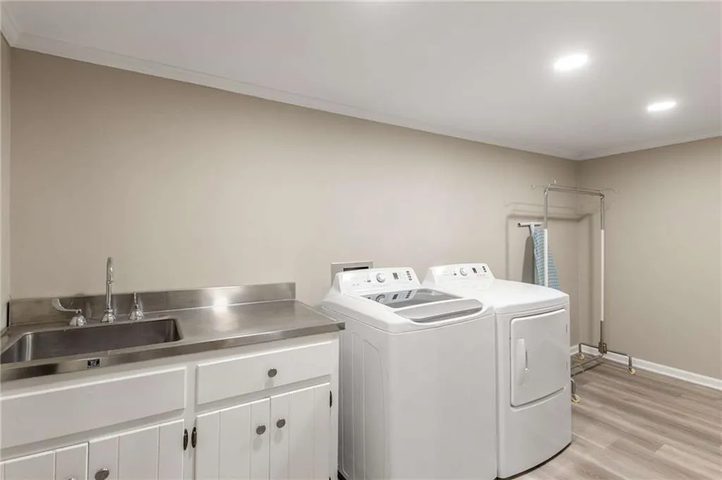 Spacious laundry area with sink, cabinets, and old laundry shoot and washer/dryer