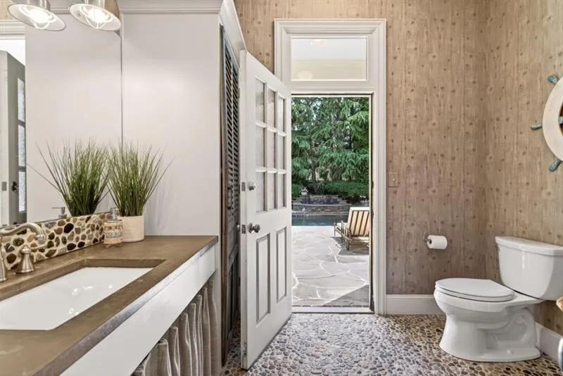 Bathroom with pebble flooring and direct outdoor access to a flagstone patio
