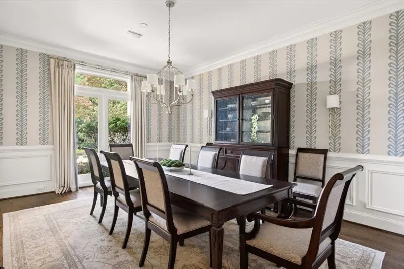 Dining space featuring wood-finish flooring, wainscoting, and patterned wallpaper