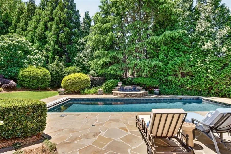 Outdoor living space featuring a rectangular swimming pool, flagstone patio, and a stone-built fountain