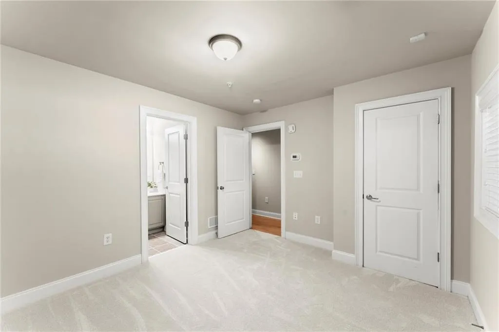 Unfurnished bedroom featuring light carpet and ensuite bathroom