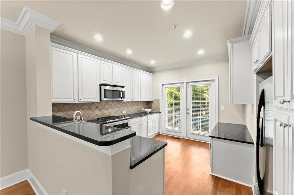 Kitchen featuring decorative backsplash, crown molding, white cabinetry, a peninsula, and light wood-style flooring