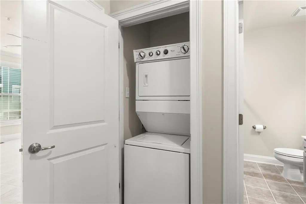 Laundry area featuring light tile patterned floors and estacked washer and dryer