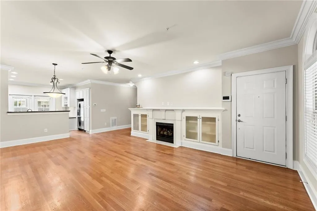Unfurnished living room with ornamental molding, a premium fireplace, light wood-style flooring, recessed lighting, and ceiling fan
