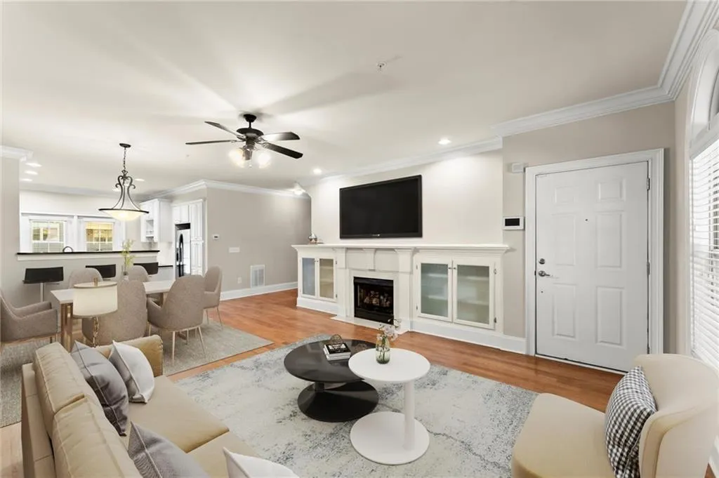 Living room featuring light wood finished floors, ornamental molding, a fireplace with flush hearth, recessed lighting, and a ceiling fan
