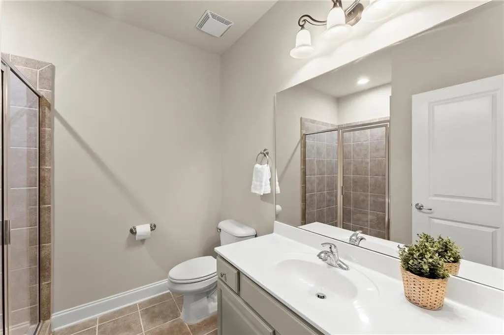 Full bath with light tile patterned flooring, vanity, and a shower stall