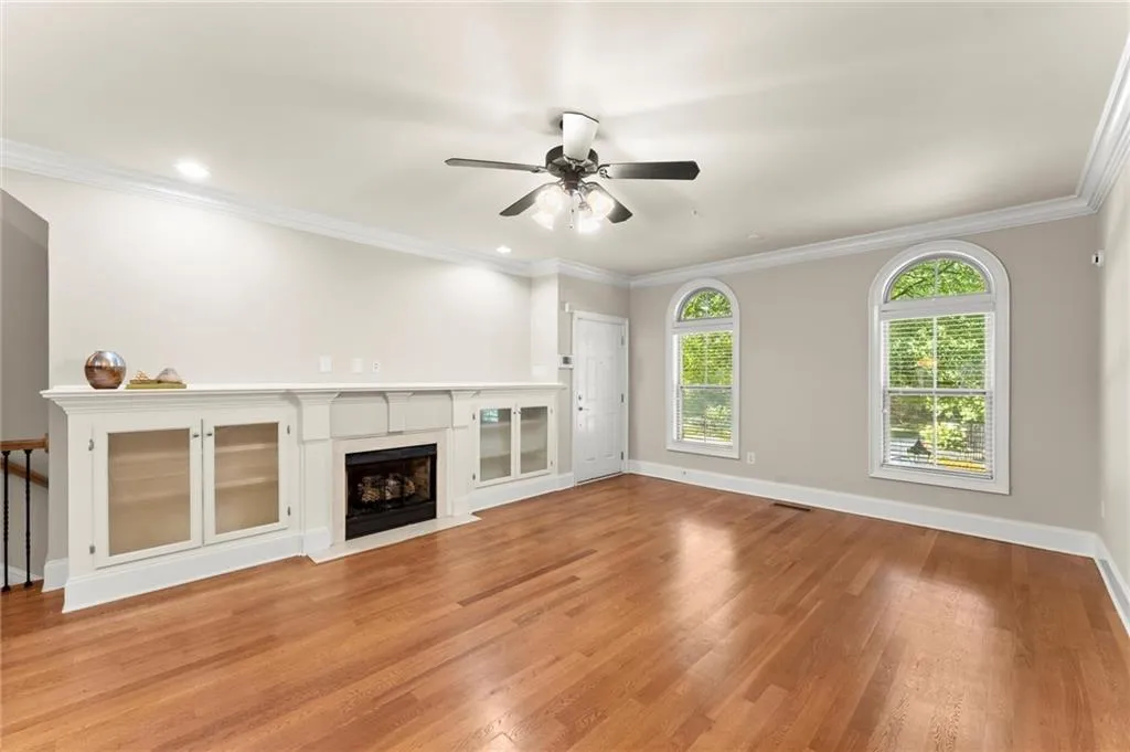 Unfurnished living room with ornamental molding, light wood-style flooring, a fireplace, and ceiling fan