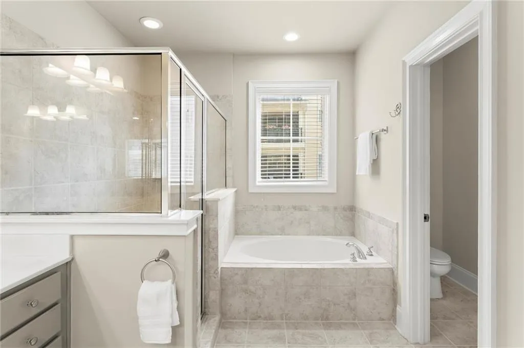 Bathroom with a stall shower, a garden tub, vanity, light tile patterned flooring, and recessed lighting
