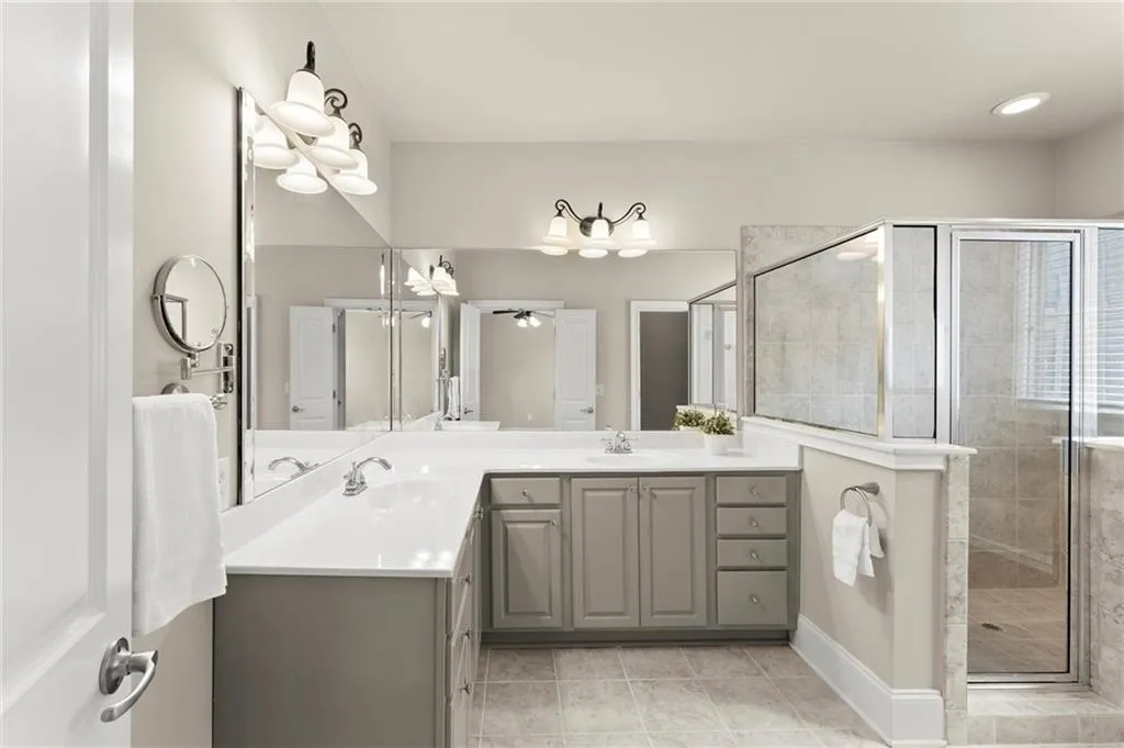 Full bathroom with double vanity, a shower stall, and light tile patterned floors