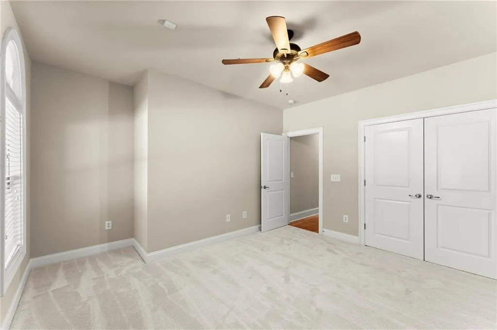 Unfurnished bedroom with light colored carpet, ceiling fan, and a closet