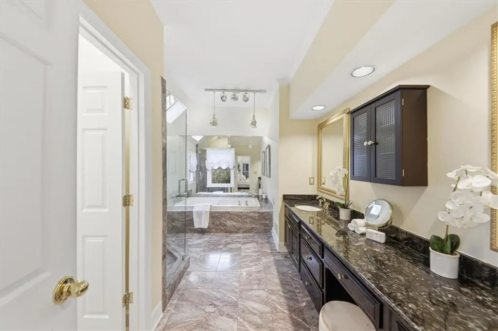 Full bath featuring a garden tub, light marble finish flooring, vanity, and a stall shower