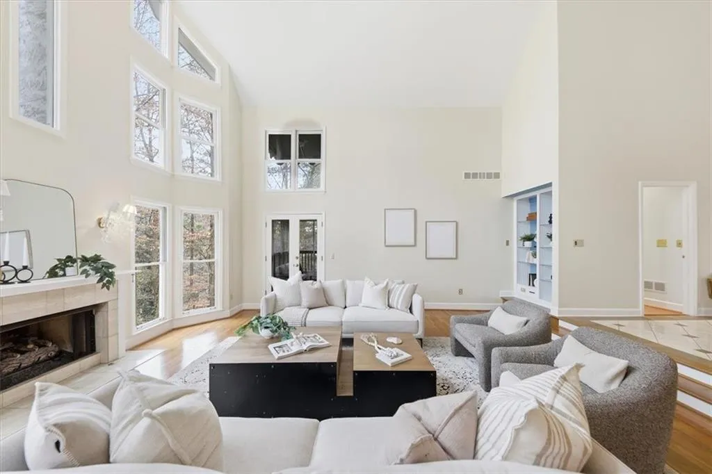 Living area with high vaulted ceiling, a tiled fireplace, french doors, and wood finished floors