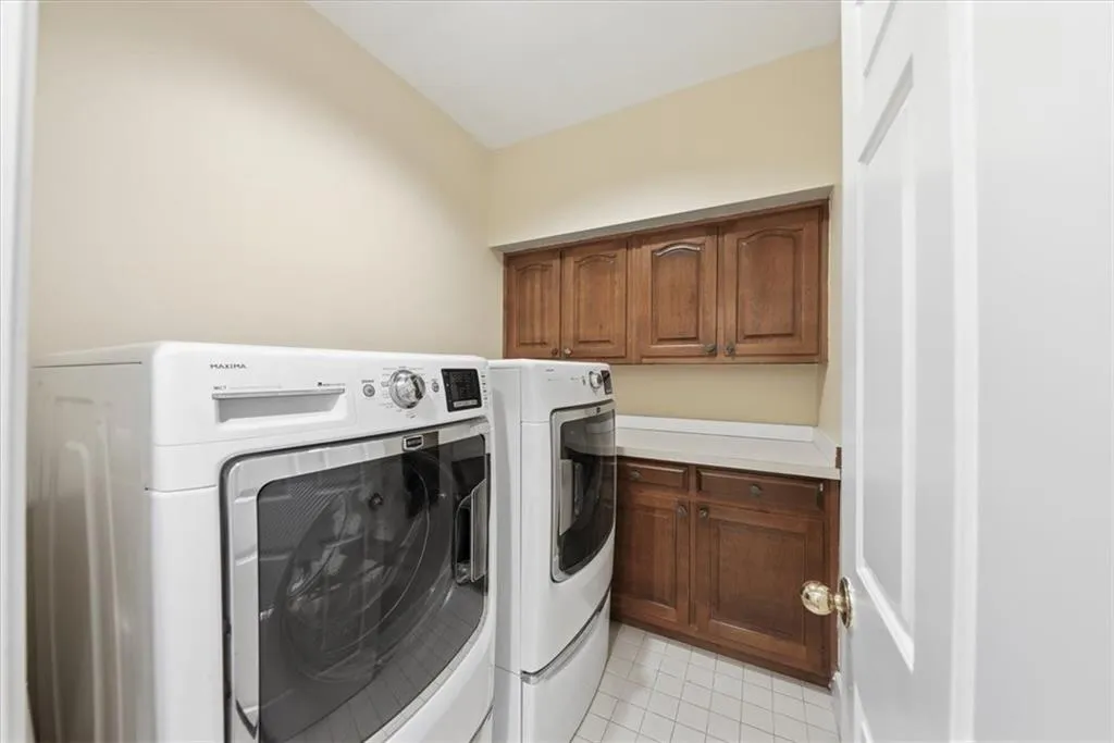 Laundry room with washer and clothes dryer, light tile patterned flooring, and cabinet space