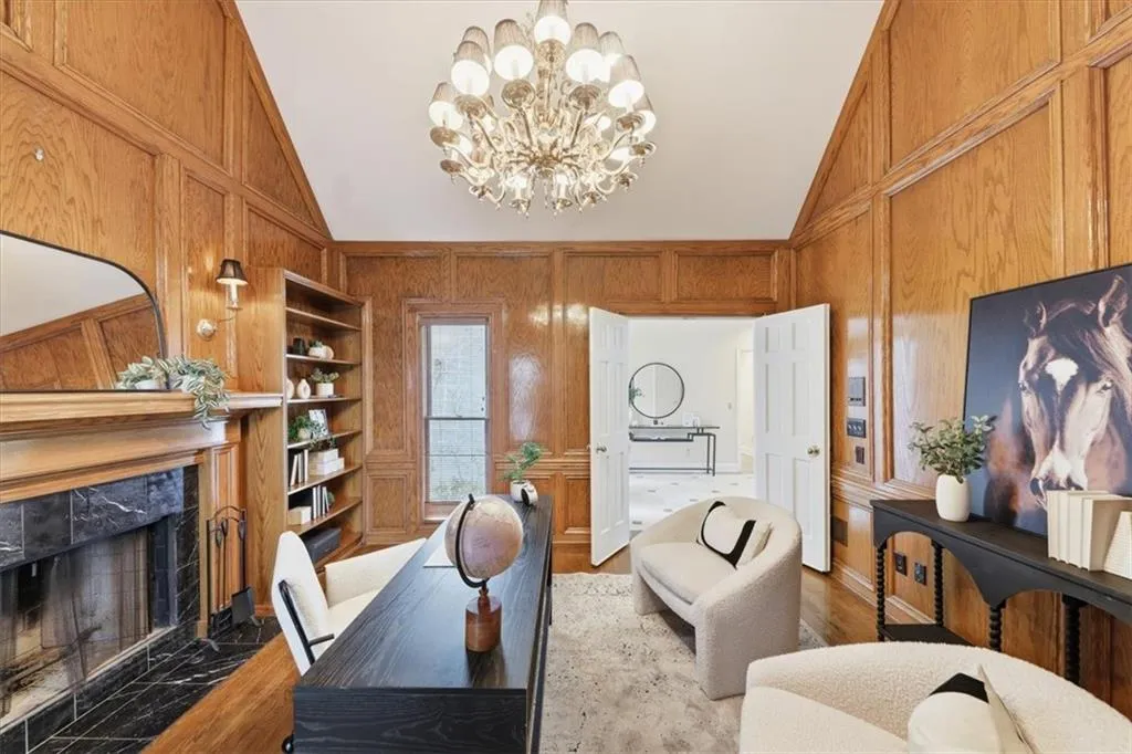 Office area with a chandelier, wood finished floors, vaulted ceiling, a premium fireplace, and wood walls