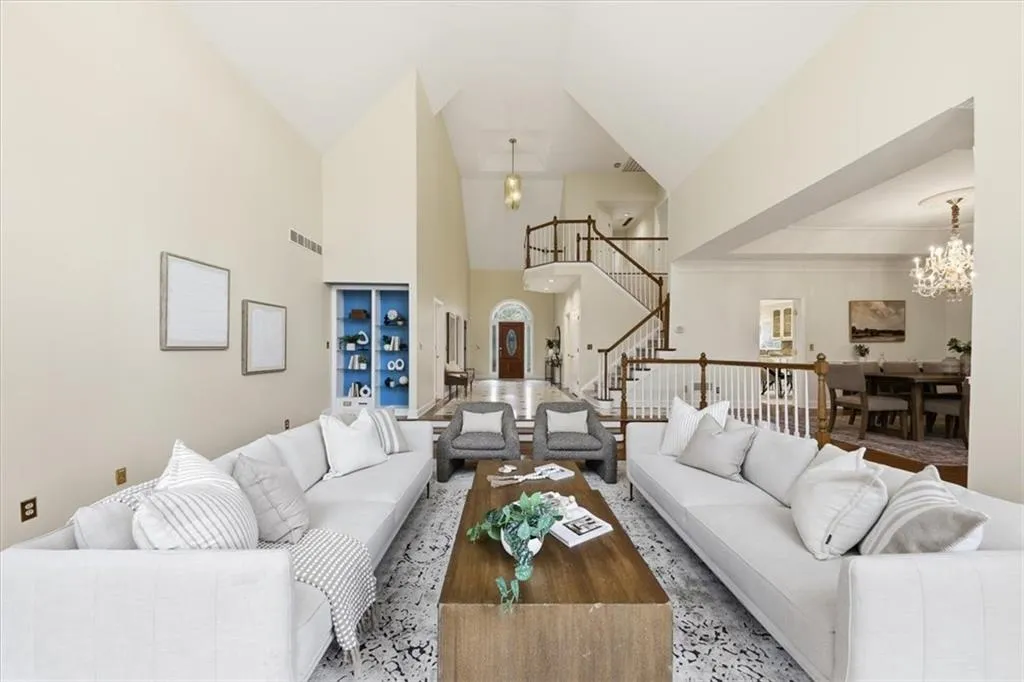 Living area with high vaulted ceiling, stairway, and a chandelier