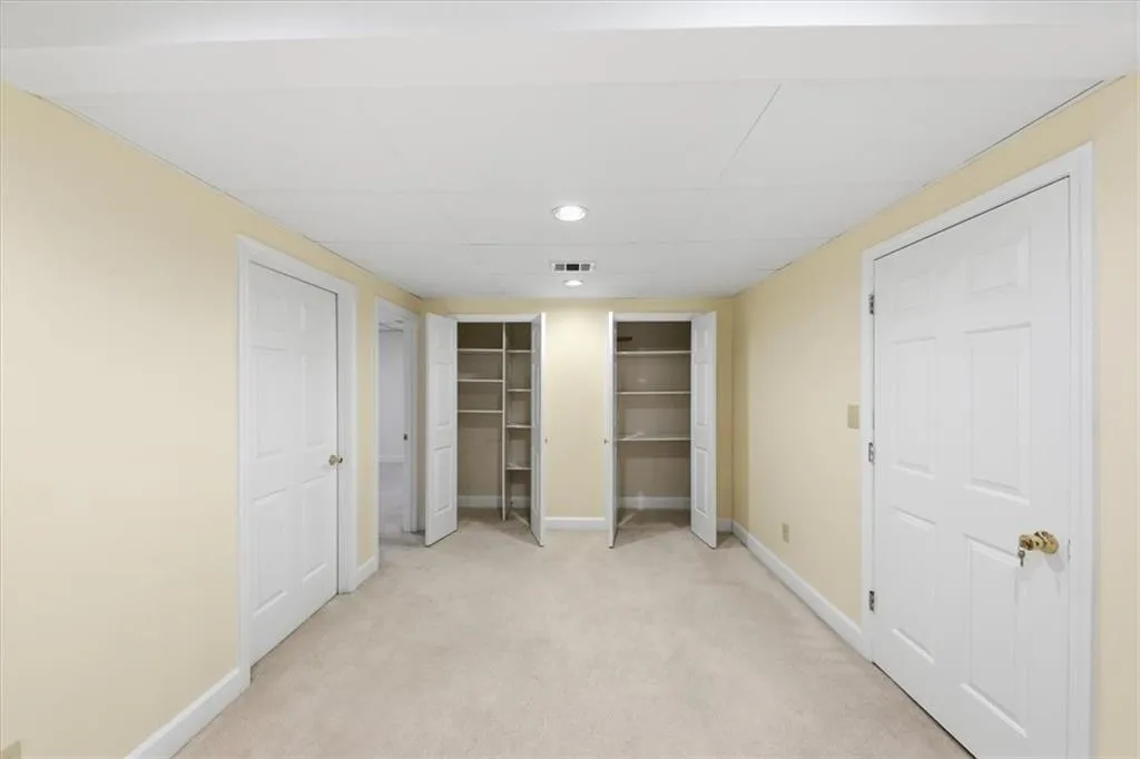 Unfurnished bedroom featuring two closets, light carpet, a drop ceiling, and recessed lighting