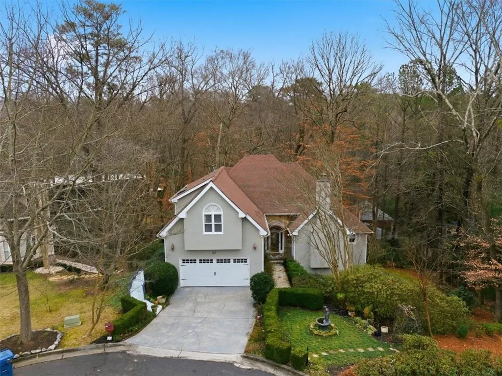 View of front facade with driveway, stucco siding, and a garage