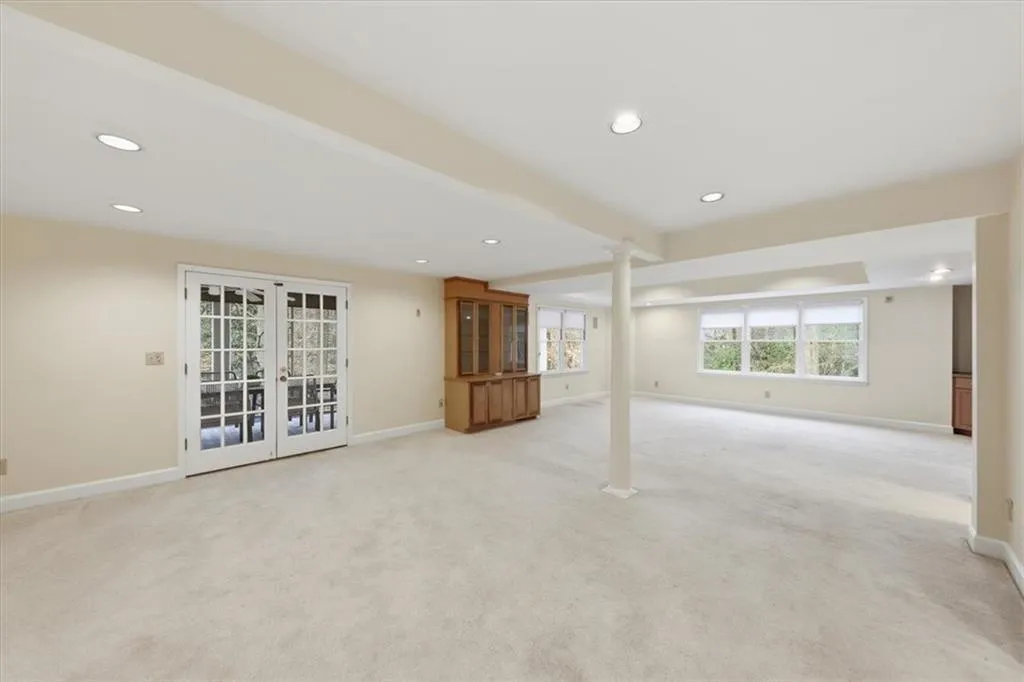 Below grade area with french doors, recessed lighting, and light carpet