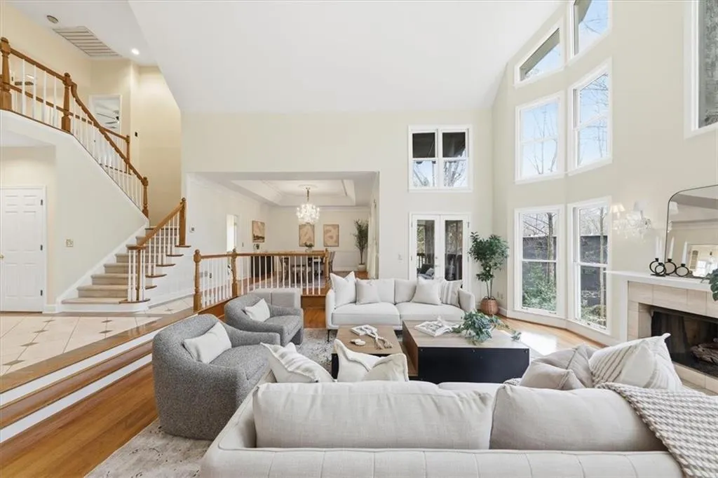 Living room with a high ceiling, a fireplace, wood finished floors, stairway, and a chandelier