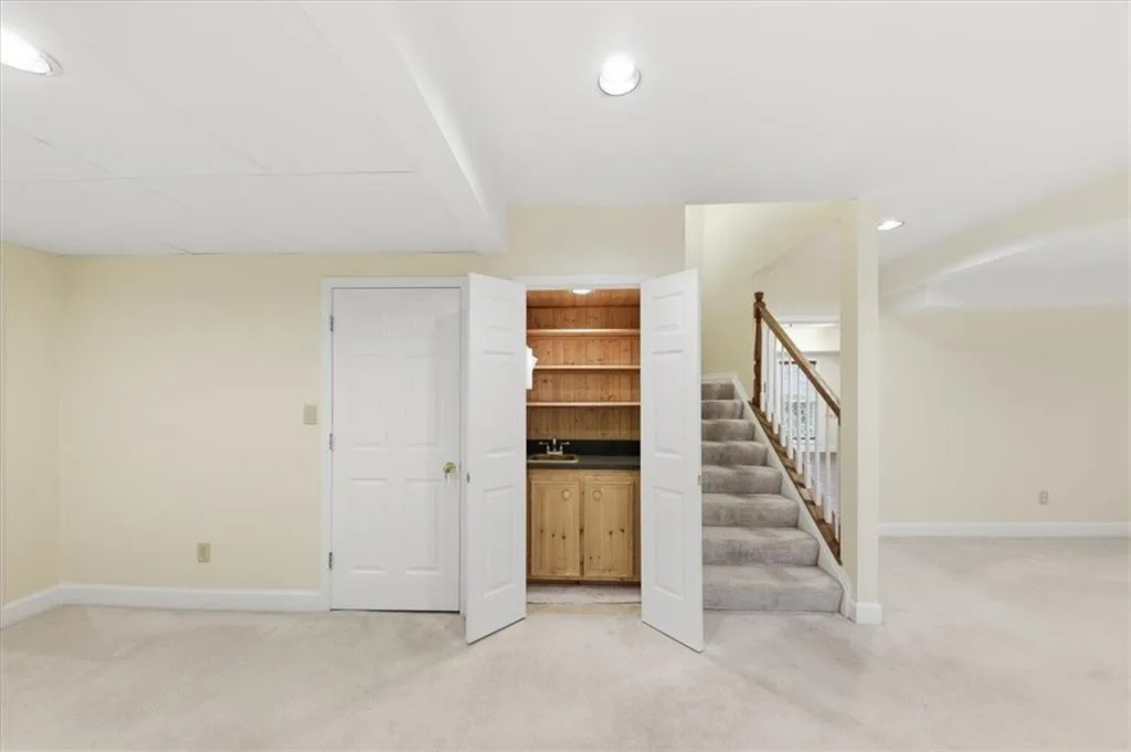 Finished below grade area with light carpet, stairway, and recessed lighting
