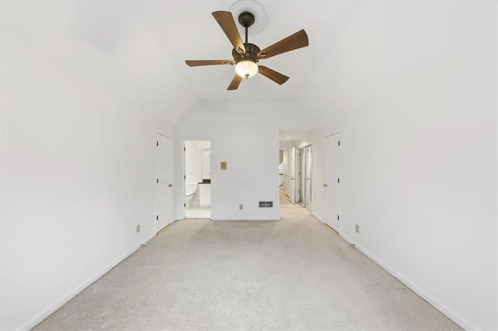 Unfurnished living room featuring a ceiling fan, carpet flooring, and vaulted ceiling