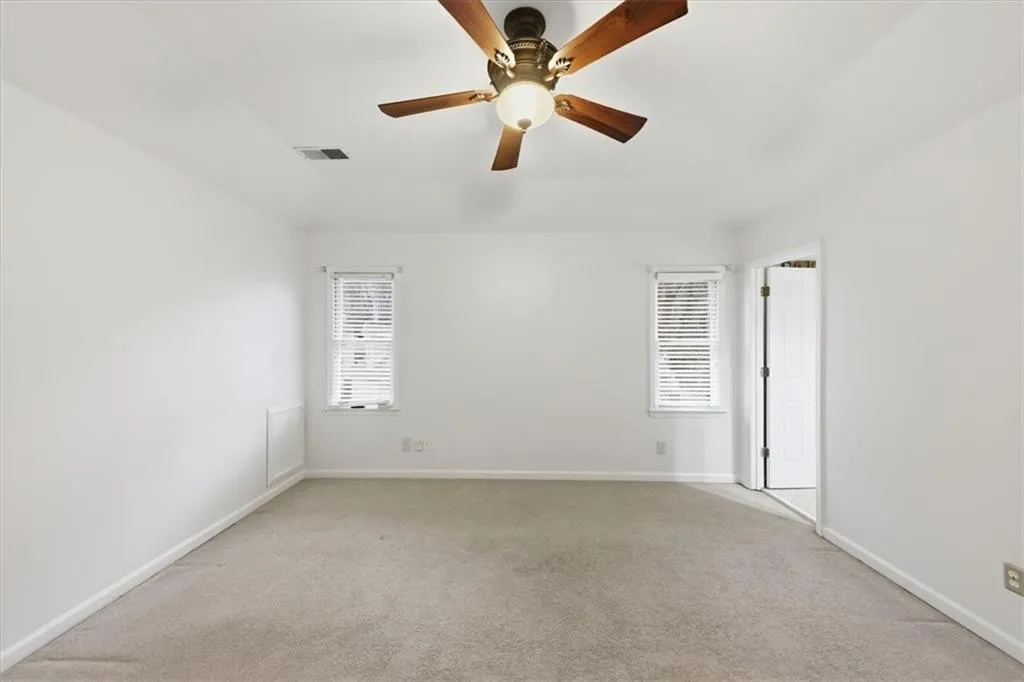 Unfurnished room with light colored carpet and ceiling fan