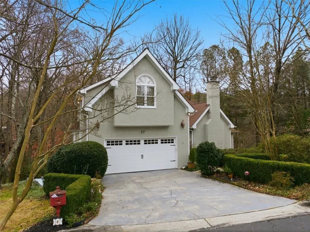 View of side of home featuring an attached garage, stucco siding, driveway, and a chimney