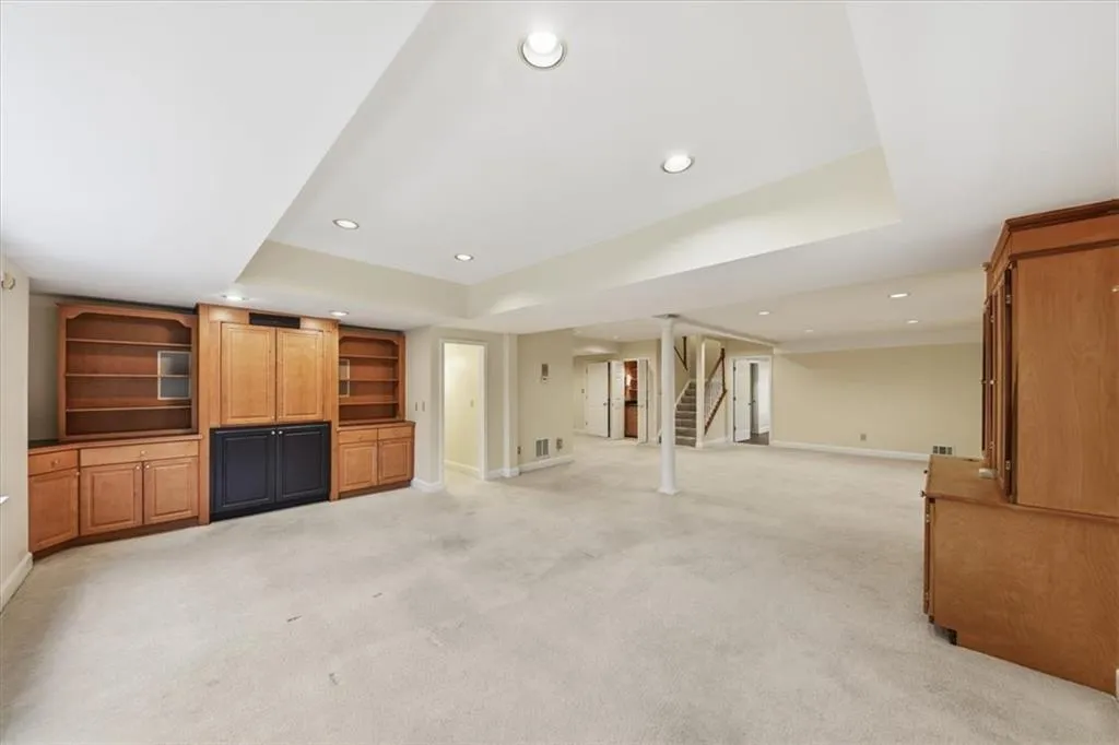 Unfurnished living room featuring recessed lighting, light carpet, stairway, and a raised ceiling