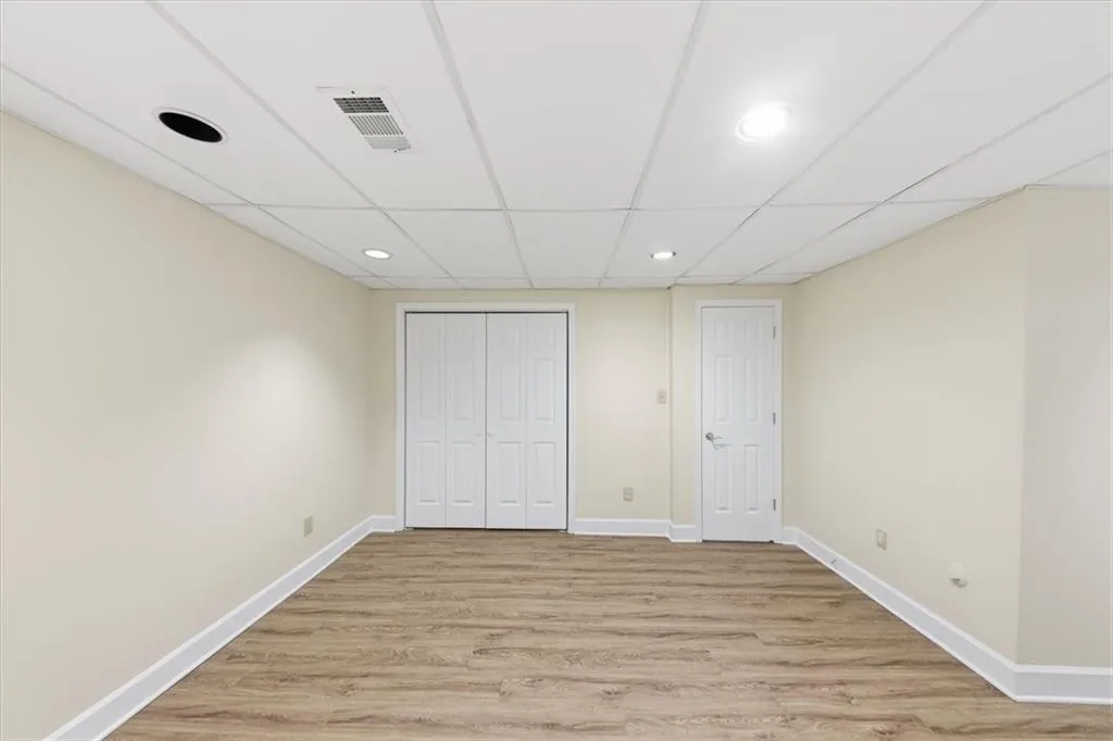 Unfurnished bedroom featuring a closet, light wood finished floors, a paneled ceiling, and recessed lighting