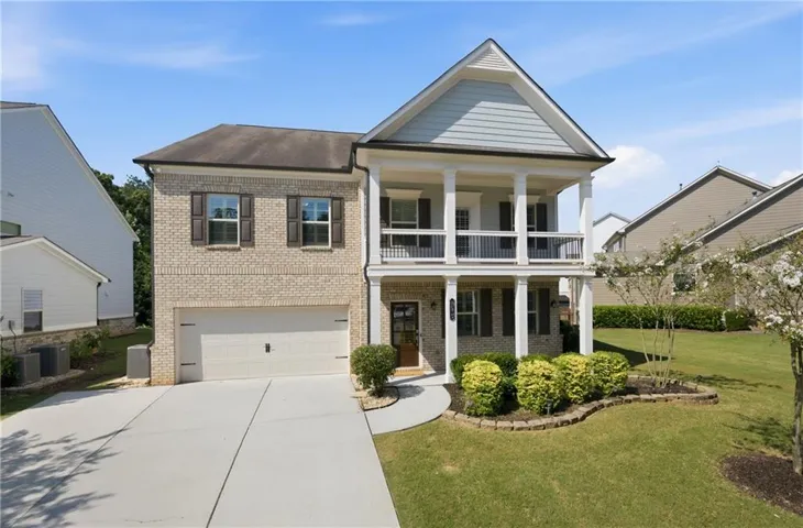 Two-story residence featuring a brick facade, double-columned front porches, and an attached two-car garage
