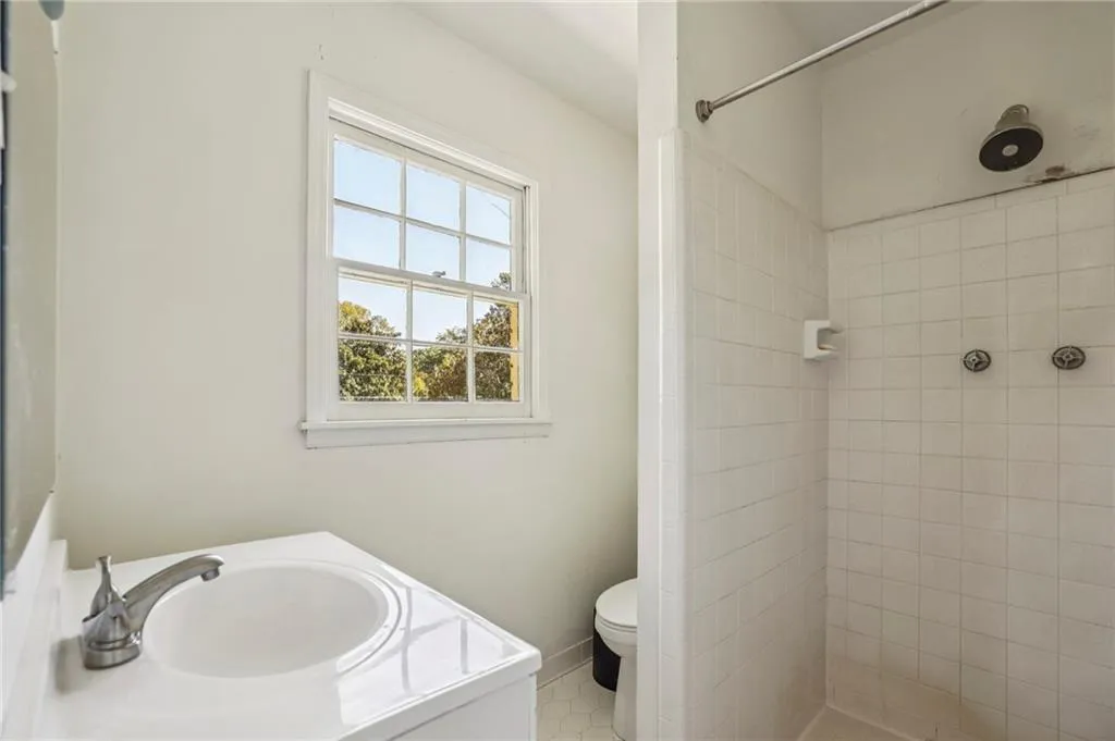 Full bathroom with vanity, tiled shower, and light tile patterned flooring