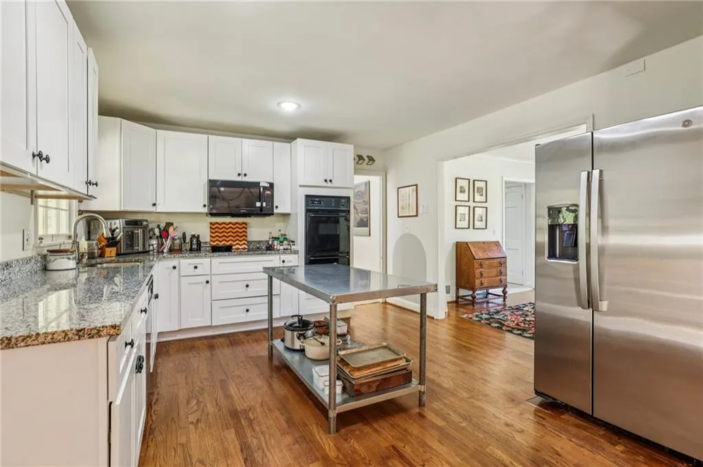 Kitchen with black appliances, dark wood finished floors, white cabinetry, light stone countertops, and recessed lighting