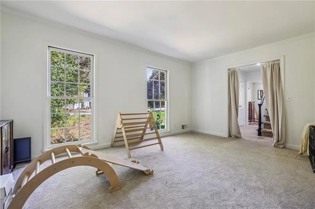 Living area featuring ornamental molding, plenty of natural light, carpet flooring, and stairway