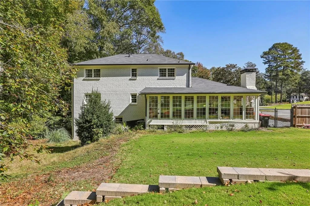 Rear view of house featuring a chimney, brick siding, and a deck