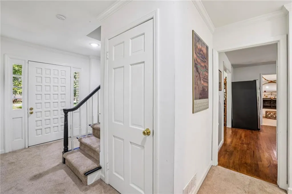 Entrance foyer featuring light colored carpet, ornamental molding, and stairway